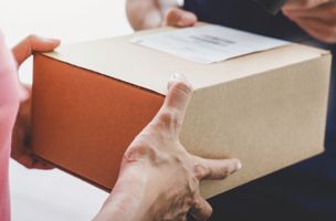 parcel being handed over at the door by a parcel delivery person and scanned to a consumer