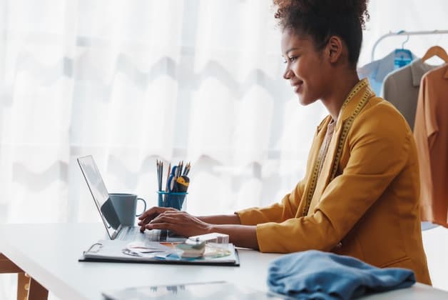 Smiling lady in a mustard jacket in front of a laptop